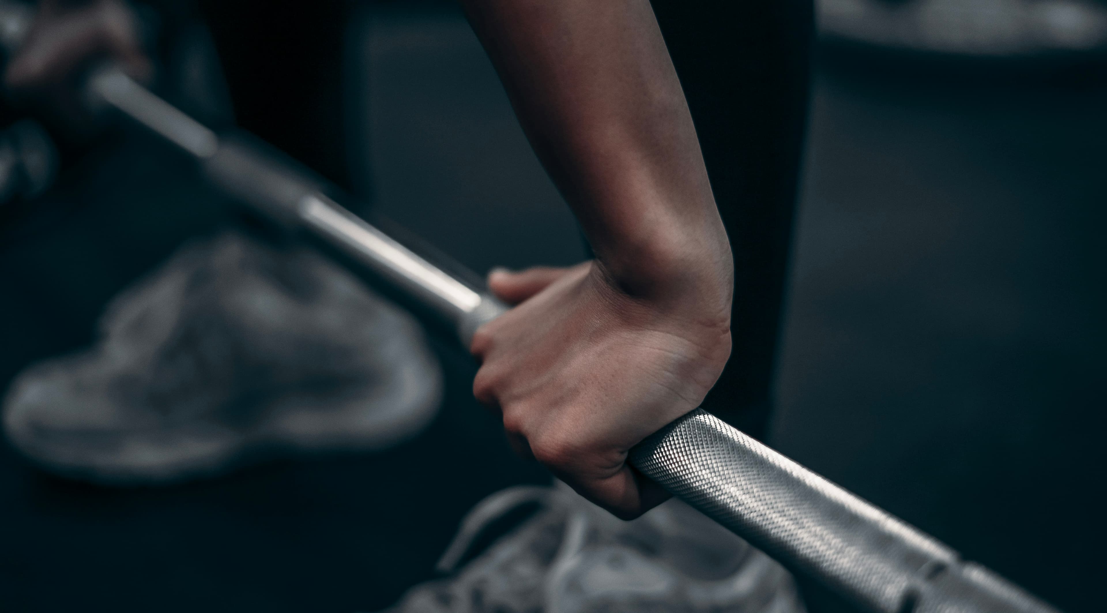Hands gripping a textured barbell during strength training
